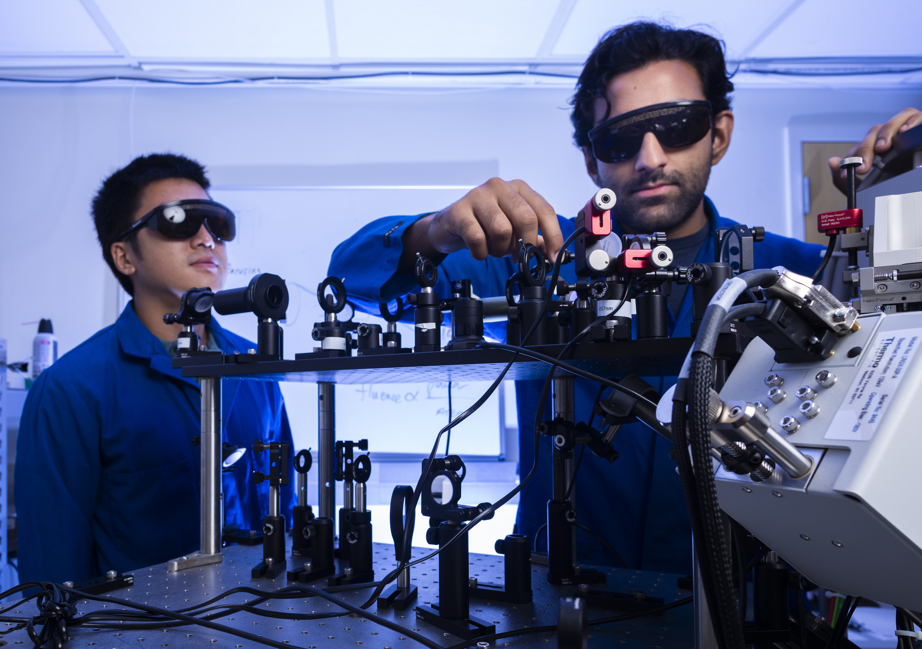 Two engineers experimenting with lasers using optical technology