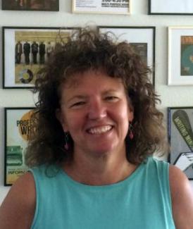 image of Madeleine Sorapure from the shoulders up in a teal shirt with a big smile